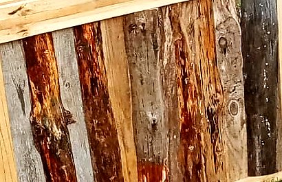 Tablas rústicas de distintos tonos, del gris al rojizo, puestas una junto a otra en el frente del bar